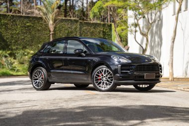 Siyah Porsche Macan önden üç çeyrek manzara, lüks arazi aracı Forest Road 'a park edilmiş.