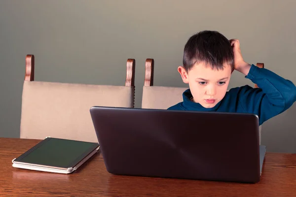 ノートパソコンとタブレットコンピュータを使って8歳の少年は頭を掻く 家庭教育やデジタル技術のテーマ — ストック写真