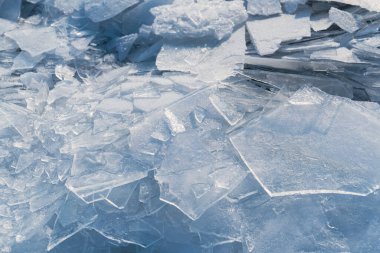 Buz parçaları donmuş bir gölü kaplıyor ve pürüzlü bir yüzey oluşturuyor. Bu sahne, soğuk havayı yansıtan keskin ve net desenlerle kışın özünü yakalar..