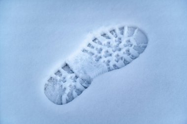 Soğuk bir kış gününde taze karda tek bir ayak izi net bir şekilde görülebilir. Lastik izleri beyaz arka planda belirgin, bu da yeni bir hareketi gösteriyor..