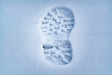 Soğuk bir kış gününde taze karda tek bir ayak izi net bir şekilde görülebilir. Lastik izleri beyaz arka planda belirgin, bu da yeni bir hareketi gösteriyor..