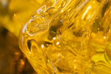 Üç parça kehribar, ışığı yansıtan siyah bir yüzeye konur. Taşlar, pürüzsüz yüzeylerini ve doğal güzelliklerini vurgulayan farklı şekilleri ve sarı tonlarını gösteriyor..