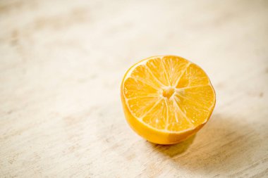 Masanın üzerinde bir dilim portakal var. Portakal ikiye bölünmüş ve içi görünür.
