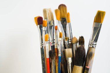 Çeşitli boya fırçalarından oluşan bir koleksiyon hafif bir arkaplana karşı dik duruyor. Bu fırçalar resim ve sanatsal faaliyetler için, farklı boyutlarda ve şekillerde kullanılmaktadır..