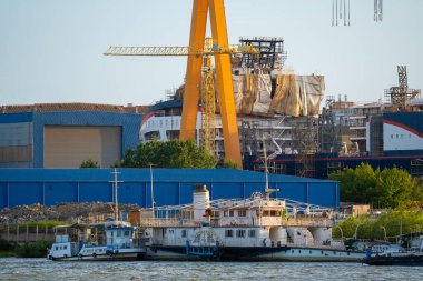 Kargo gemileri yoğun bir limana demirli iken vinçler malzemeleri kaldırır. Endüstriyel yapılar temiz bir gökyüzünün altında bölgeyi çevreledi. İşçiler sahnede aktifler.