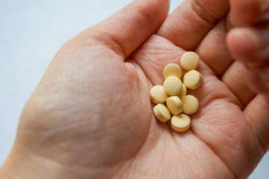 İnsan eli birden fazla sarı tablet tutuyor.