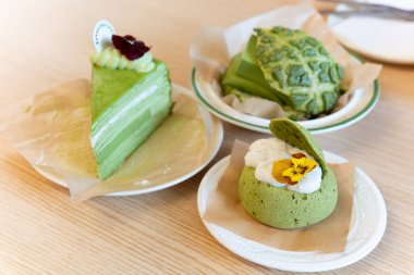 Beyaz bir yüzeyde yeşil çay eşliğinde yakın plan bir tatlı.