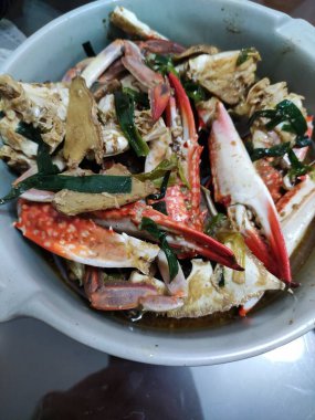 Masadaki beyaz seramik kasede yeşil soğanlı kızarmış yengeç.