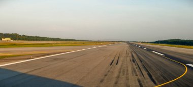 Kalkış ya da kalkışa hazırlanan bir uçaktan alınan bir havaalanı pisti manzarası. Pistte beyaz eşik izleri ve sık inişlerden kaynaklanan patinaj izleri bulunuyor..