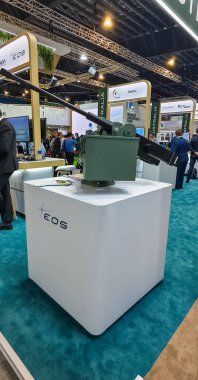 Uzaktan kumandalı silah istasyonu savunma sergisinde sergileniyor. EOS (Elektro Optik Sistemler) tarafından çevrelenmiş askeri yeşil uzaktan kumandalı silah istasyonu, havacılık ve savunma bölmeleri ile çevrilidir..