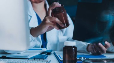 Tıbbi ekip, beyaz laboratuvar önlüklü ve ameliyat önlüklü doktorlarla toplantı yapıyor. Masada oturmuş, internette çalışan hastaları tartışıyorlar. Tıp endüstrisinde bilgisayar kullanıyorlar..