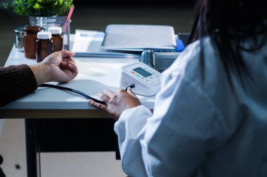 Bir doktorun elleri dikkatle hastanın kan basıncını ölçmek için sfenometre kullanıyor..