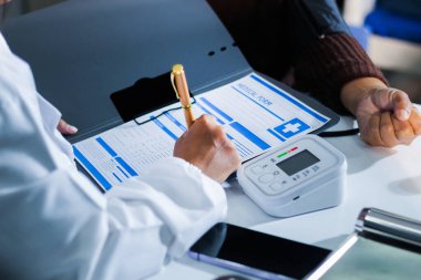 Bir doktorun elleri dikkatle hastanın kan basıncını ölçmek için sfenometre kullanıyor..