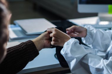 Bir doktorun elleri dikkatle hastanın kan basıncını ölçmek için sfenometre kullanıyor..