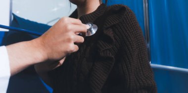 Sağlık kontrolü sırasında hastanın kalbini incelemek için steteskop kullanan bir doktor.