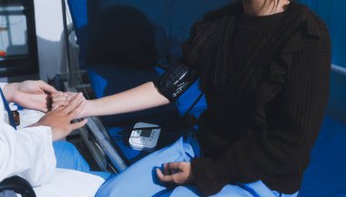 Doktor genç kızı muayene ediyor, kan basıncını ölçüyor, tansiyon monitörü kullanıyor. Okula giriş sınavı kavramı.