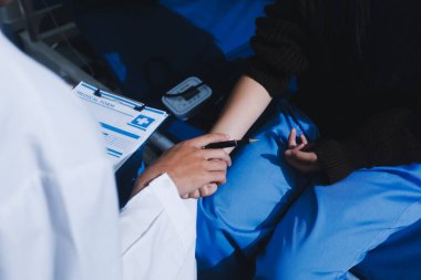 Hastanedeki doktor, kadının kan basıncını ve nabzını ölçmek için manuel tansiyon monitörü kullanıyor..