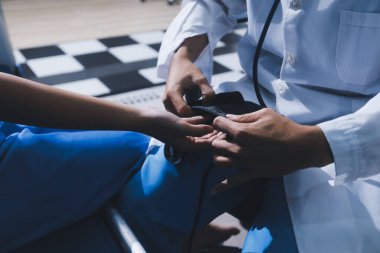 Hastanedeki doktor, kadının kan basıncını ve nabzını ölçmek için manuel tansiyon monitörü kullanıyor..