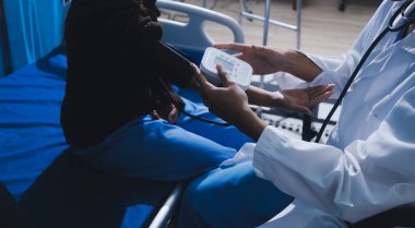 Doctor in hospital using manual blood pressure monitor to measure woman patient blood pressure and pulse.