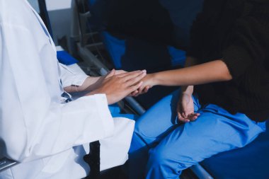 Doktor hastanın elini tutuyor ve ona destek oluyor.