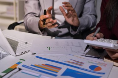 İş adamları, ofiste birlikte çalışırken gelecekteki işleri için strateji oluşturmak ve plan yapmak amacıyla aylık bütçe ve mali raporu analiz ediyorlar..