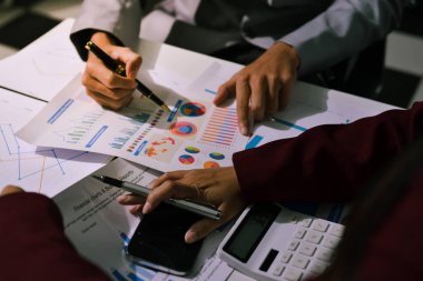 İş adamları, ofiste birlikte çalışırken gelecekteki işleri için strateji oluşturmak ve plan yapmak amacıyla aylık bütçe ve mali raporu analiz ediyorlar..