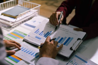 İş adamları, ofiste birlikte çalışırken gelecekteki işleri için strateji oluşturmak ve plan yapmak amacıyla aylık bütçe ve mali raporu analiz ediyorlar..