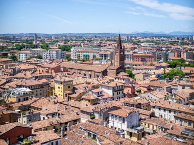 Verona üzerinde geniş çatı manzarası var. Terracotta Çatıları, Kilise Kuleleri, Uzak Tepeler, Yamalı sokaklar, Sıcak