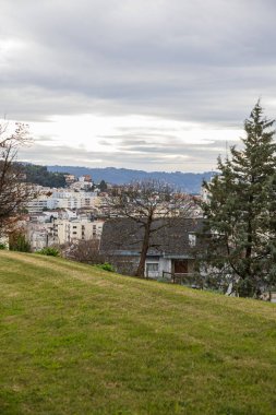 Grassy Hillside Braga Şehrine Bakış, Bulutlu Gökyüzü ve Uzak Çatılar. Yuvarlanan çim, dağılmış ağaçlara ve konut bloklarına yol açar.