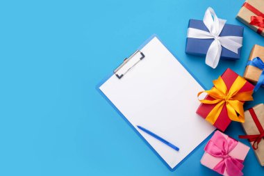 Boş bir sayfa ve mavi arka planda hediyeler. Hediye alışverişi konsepti.