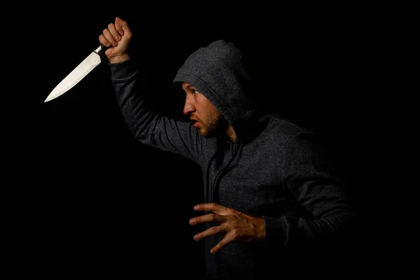 Aggressiver Junger Mann Mit Kapuze Schwingt Messer Vor Schwarzem Hintergrund — Stockfoto