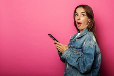 Kot ceketli genç bir kadının pembe arka planda telefonu tutmasına şaşırdım.
