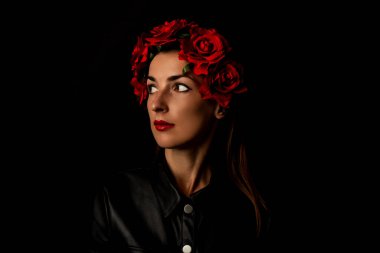 Siyah arka planda kırmızı çiçekli dalgın genç kadın.