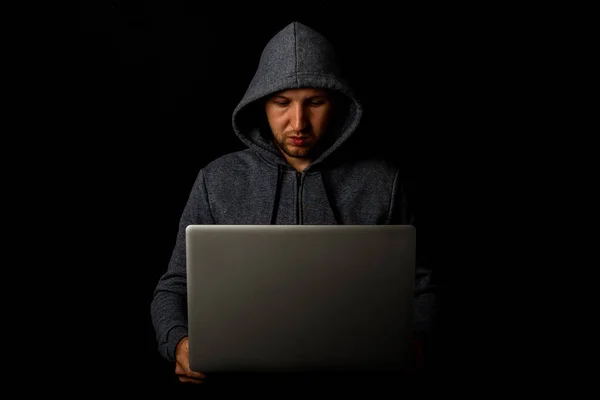 Uomo Con Cappuccio Tiene Portatile Tra Mani Uno Sfondo Scuro — Foto Stock