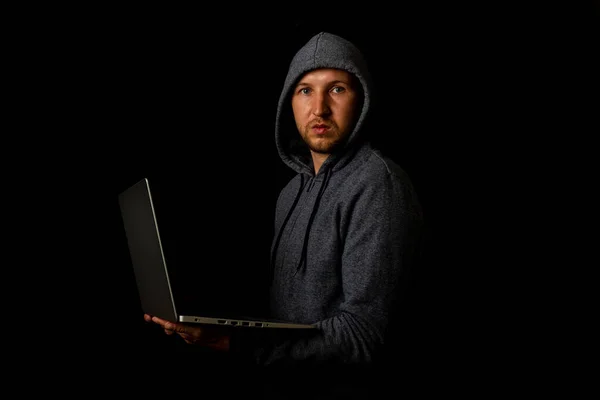 Hombre Con Capucha Sostiene Portátil Sus Manos Sobre Fondo Oscuro —  Fotos de Stock