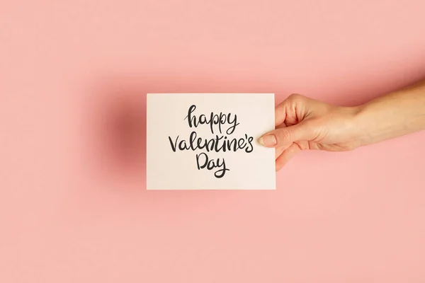 Die Weibliche Hand Hält Eine Karte Auf Pastellrosa Hintergrund Valentinstag — Stockfoto