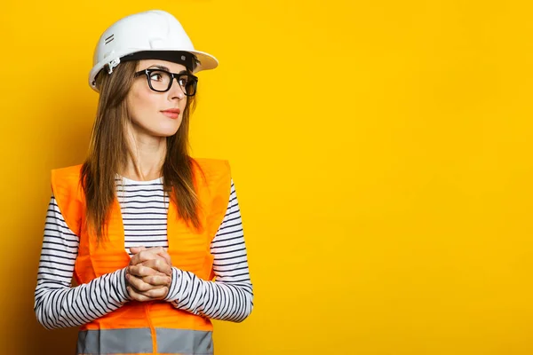 Young woman in a vest and hard hat on a yellow background. Construction concept, new building. Banner.