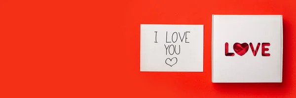 赤い背景にテキストの愛とカードとギフトボックス 作曲バレンタインデー バナーだ フラットレイアウト トップビュー — ストック写真