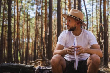 Kamp gezisi sırasında elinde harita tutan şapkalı bir adam. Dağlarda yürüyüş, orman....