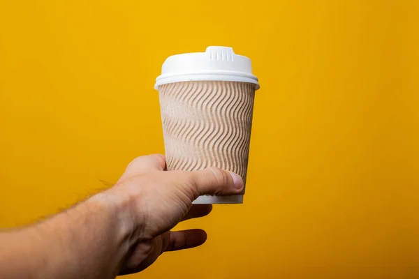 Mano Masculina Sirve Vaso Cartón Sobre Fondo Amarillo — Foto de Stock