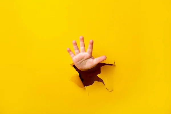Children Hand Sticks Out Hole Sheet Paper Yellow Background Five — Stock Photo, Image