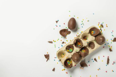 Kırık Paskalya çikolatalı tepsi ve açık arkaplanda çok renkli şeker süslemeleri. Paskalya konsepti, paskalya hediyeleri, tavşancık. Pankart. Düz yatış, üst görünüm.