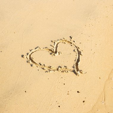 Kumsalın kumlarına el çizimi kalp sembolü. Yaz tatili, aşkım.