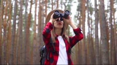 Kadın turist ormandaki dürbünlerden bakar. Yürüyüş kavramı, turizm.