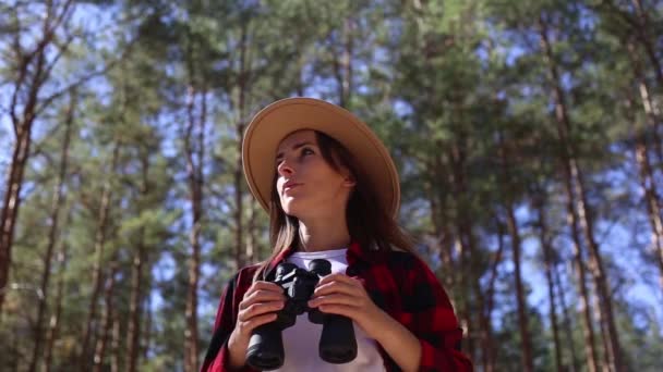 Ormanda yürürken şapkalı bir kadın dürbün tutuyor. Yürüyüş kavramı, turizm. — Stok video