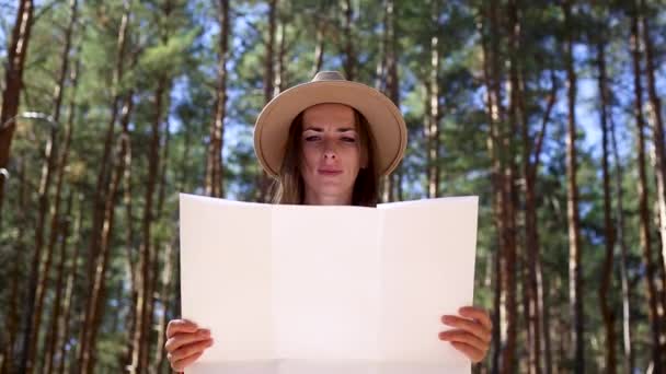 Şapkalı kadın ormandaki haritaya bakıyor. Yürüyüş kavramı, turizm. — Stok video