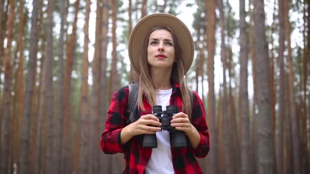 Femeia turistică cu binoclu se uită în jur în pădure. Excursie concept, turism . — Videoclip de stoc