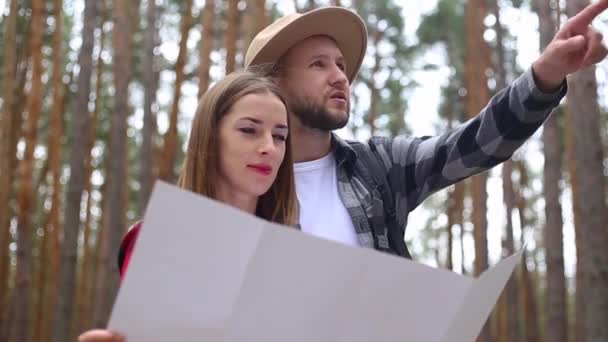 Mujer y un hombre excursionistas están mirando un mapa y buscando una ruta en el bosque. Concepto caminata, turismo. — Vídeo de stock