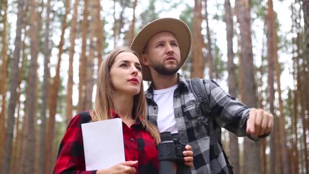 Mujer y un hombre excursionistas están mirando un mapa y buscando una ruta en el bosque. Concepto caminata, turismo. — Vídeo de stock