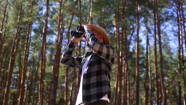 Turista masculino mira a través de prismáticos en el bosque. Composición senderismo, forestal. — Vídeo de stock